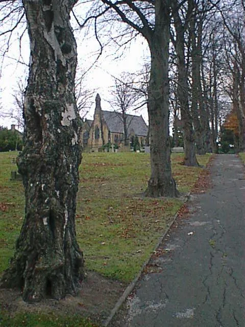 View northeast along one of the paths in the cemetery at Churchside, Hasland, Derbyshire, with St Paul's parish church in the distance