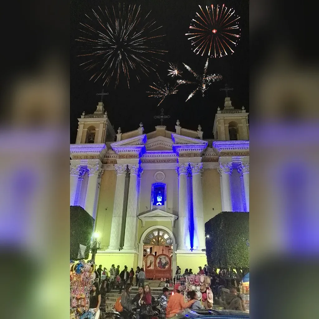 Podemos observar la Catedral ubicada en el parque central y en el cielo obscuro lo iluminan los juegos pirotécnicos que son utilizados cuando entidades municipales dan por inaugurada la Feria Titular en Honor a la Virgen del Carmen. Huehuetenango, Guatemala.