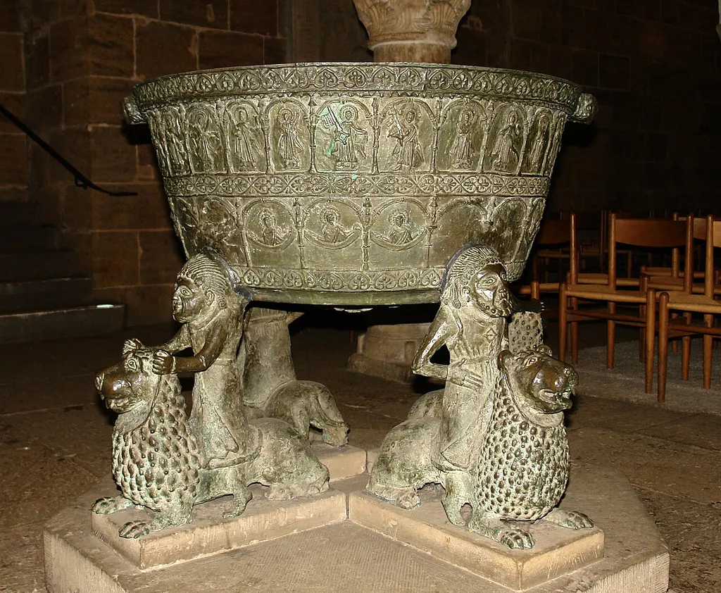 Bremer St. Petri Dom: Taufbecken (um 1220) in der Westkrypta. Ein Meisterwerk spätromanischer Bronzegießkunst, das zu den prächtigsten und ältesten dieser Art zählt. Die Bedeutung der vier auf Löwen reitenden Figuren ist nicht geklärt. In den oberen Rundbögen sind 26 Figuren dargestellt, in den unteren 12 Halbfiguren. (Qu.: Der Dom zu Bremen, ISBN 3-7845-4231-X)