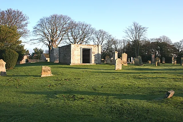 Spynie Kirkyard This was the site of the original kirk of Spynie until a new kirk was built about six miles to the west at Quarrywood. It is still in use as a burial ground. The gable of a new bungalow is visible over the kirkyard wall, and Spynie House is hidden among the trees.