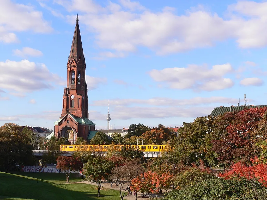Berlin-Kreuzberg, Germany – Emmauskirche on Lausitzer Platz, seen from Görlitzer Park, subway (line 1, driving above streetlevel) crossing in front of the church