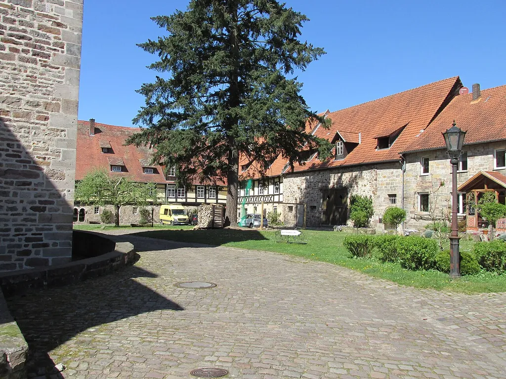 Blick von der östlichen Zufahrt in den Klosterhof des ehemaligen Klosters von Lippoldsberg, im Hintergrund von links nach rechts: das Haus Klosterhof 10 mit gelber Fassade, die Rückseite des Hauses Wüste 14, die Scheune des Hauses Klosterhof 8 und ein Teil des Hauses Klosterhof 8