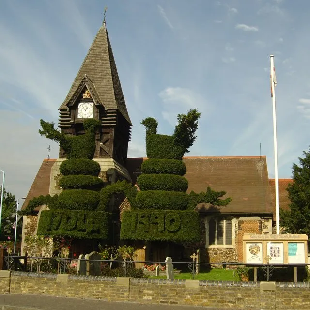 Parish church of St Mary the Virgin, Staines Road, East Bedfont, Middlesex, seen from the southeast. In front of it is a large work of historic topiary, thought to represent peacocks.