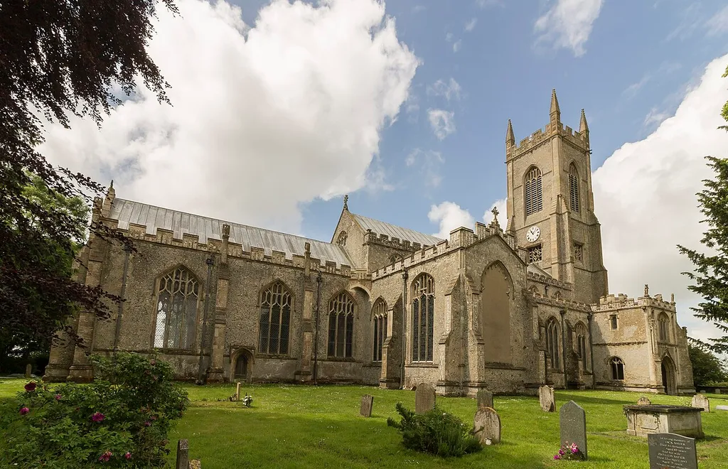 Grade I listed This large perpendicular church in a relatively remote location was built between around 1405 and 1420. It was financed by at least four Lords of Manors and other men with wealth acquired from wool. There were at least six Guilds Chapels, and a chaplain and clerks in each Chapel prayed daily for donors' souls. There is a west tower, north and south porch with parvises, nave with clerestory, north and south aisles, north and south transepts and chancel. The west tower is of four stages, the last stage was built around 1511. There is a west door with censing Angels and Shields over it. The centre of the tower has a "sound hole" with delicate tracery. The top has richly decorated battlements. There are eight bells. The north and south porches are of two storeys, with stair turret access. The north porch parvise has a vaulted ceiling with carved bosses. There is the remains of a piscina, and this was probably a Lady Chapel. The south porch has a standard beamed roof, and the parvise was probably a Treasury, as the timbers of the roof have iron bands for protection. The nave has six-bay arcades, the piers having four shafts. There is a tall clerestory, and a window over the chancel arch. The chancel has a seven light east window of plain glass with some mediaeval glass in the tracery depicting the nine orders of Angels. The south transept has a four light south window and a three light east window. There is some mediaeval glass in the traceries. The north transept, originally a Chapel of Thomas Rose, d. 1441, was restored in 1910 by Sir Alfred Jodrell. He donated three stained-glass windows, some of which have original glass in the tracery. The western window represents the history of the church. The top four lights of the west window contain a message "Hear this ye old men and give ear all ye inhabitants of the land, hath this been in your days or even in the days of your fathers?". The north window has been blocked. The roof, like many other East Anglian