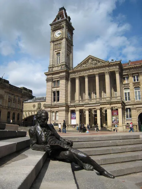 Chamberlain Square — with the reclining sculpture of Thomas Attwood, the Chartist Leader and first MP for Birmingham. The sculpture was a collaboration between sculptors Sioban Coppinger and Fiona Peever. It was commissioned by Priscilla Michell in conjunction with the City of Birmingham to commemorate her great great grandfather. The backdrop is the Birmingham Museum and Art Gallery with the clock tower of "big Brum".
