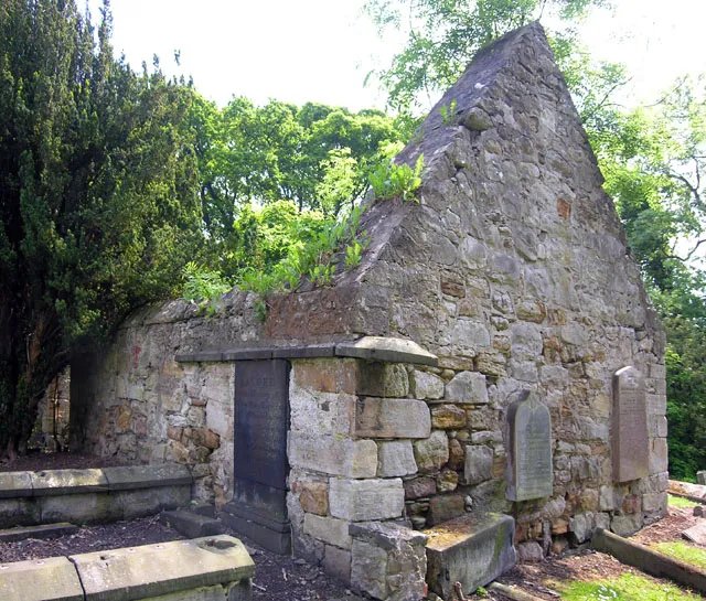 Crombie Old Church Ruin Southish West Corner Just across the narrow road (Brae) from this church is marked on old maps as being a windmill. This sizeable collection of buildings is currently being developed  possibly housing  I hope they upgrade the very narrow single track road. Not much chance of anyone renovating this old church that looks like a giants window box. The stonework is in a very dangerous condition. Inside the walls of the church, right in the middle of the floor, stands a bit of an oddity. A large gravestone, nearly three feet wide and over six feet tall. I was not brave enough to risk life and limb for a closer look.