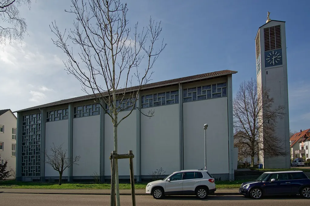 Evangelische Trinitatiskirche, Durlach. Evangelische Trinitatiskirche in Durlach-Aue mit Pfarrzentrum, 1962/64 nach Plänen von Friedrich Remspecher aus Freudenstadt, Kirche mit rechteckigem Grundriss mit sieben quer gestellten Betonstützen, bis zum Oberlicht in Ziegelmauerwerk ausgefüllt, Belichtung mit Betonstegraster, freistehender Turm, dekorative Verglasung in Blau-Weiß-Rot nach Entwurf von Prof. K. Arnoldaus Karlsruhe, Dünne Stützen tragen die Stahlbinderkonstruktion im Innenraum, Holzriemenverkleidung der Decke mit zeltartigem Charakter, Chorrückwand mit Klinkerwand und verglastem Kreuz. Geschützt nach § 2 Denkmalschutzgesetz Baden-Württemberg
