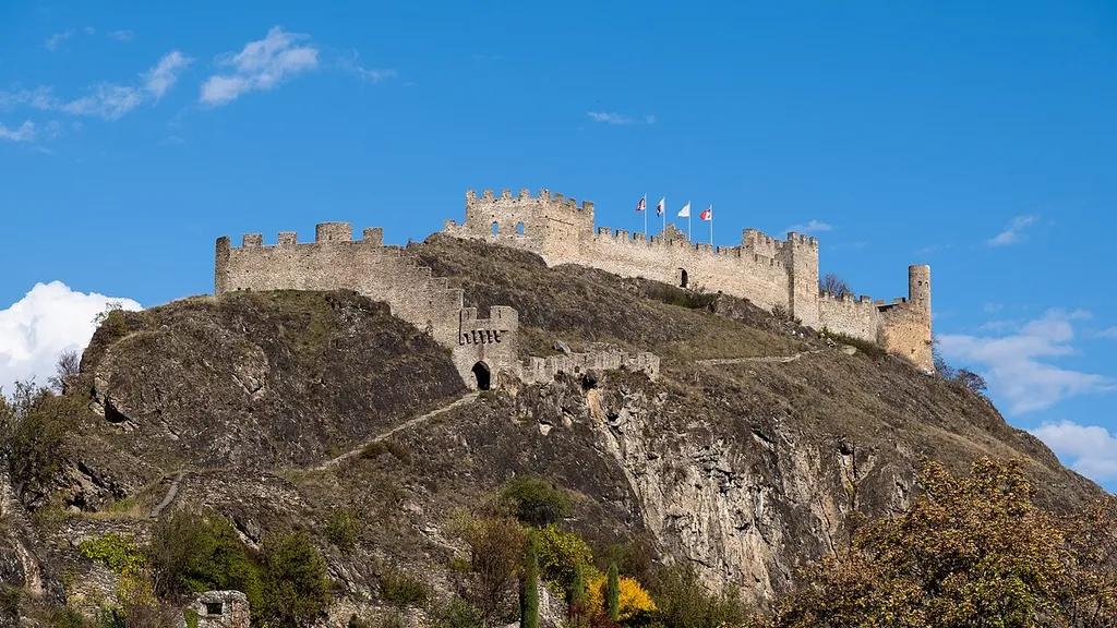 Le château de Tourbillon vu depuis la terrasse du château du Vidomnat (musée d'Art du Valais). Une prairie/un pâturage sec d'importance nationale s'étend sur les versants au-dessus des vignobles.