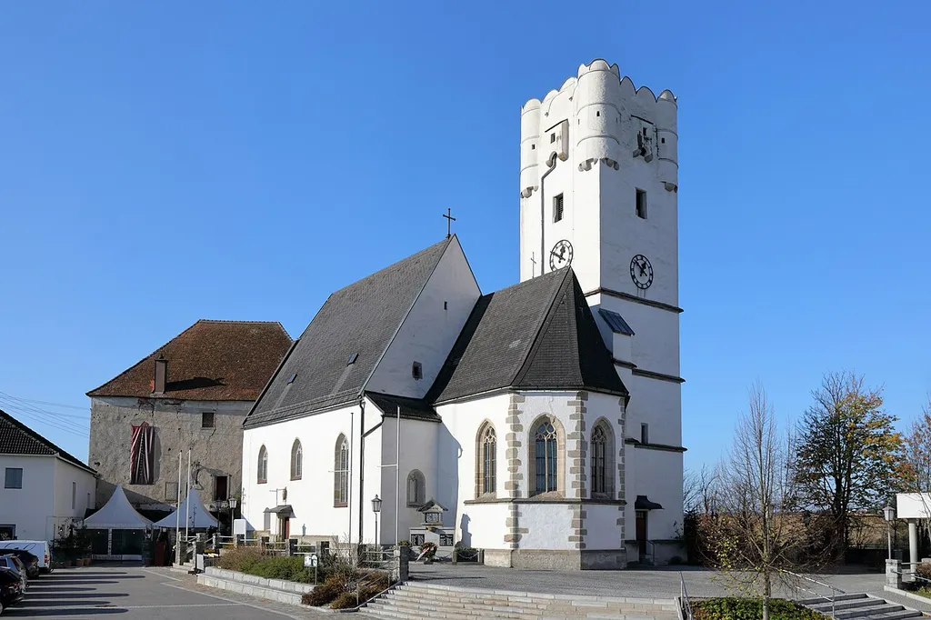Ostsüdostansicht der röm.-kath. Pfarrkirche hl. Johannes der Täufer in der oberösterreichischen Gemeinde Arbing. Die Pfarrkirche, errichtet Ende des 15. Jahrhunderts, ist ein zweischiffiger Kirchenbau auf dem Schlossberg und mit dem markanten Kirchturm, der ursprünglich ein Wehrturm war, weithin sichtbar.