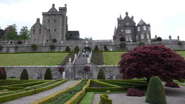 Front elevations of the old and the new at Drummond Castle This photograph gives a good view of the terrace and ornamental steps descending to the gardens below. The public entrance to the gardens is through the courtyard (unseen) adjacent to the old tower on the left.