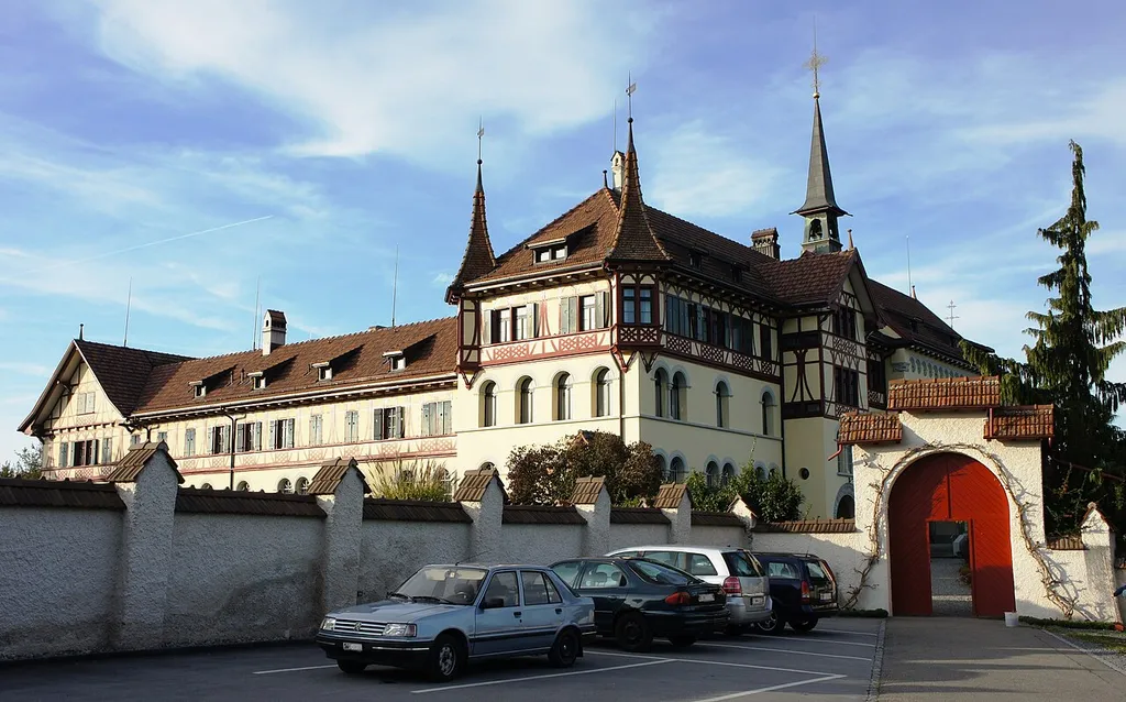 Das Kloster Scholastika in Tübach vom Parkplatz aus (von Südosten). Rechts das Eingangs-Tor zum Vorplatz (Zugang zur Kirche und Pforte). Links hinter der Mauer ist der Klostergarten (Klausur-Bereich). In der Mitte der Haupttrakt und rechts davon die Klosterkirche.