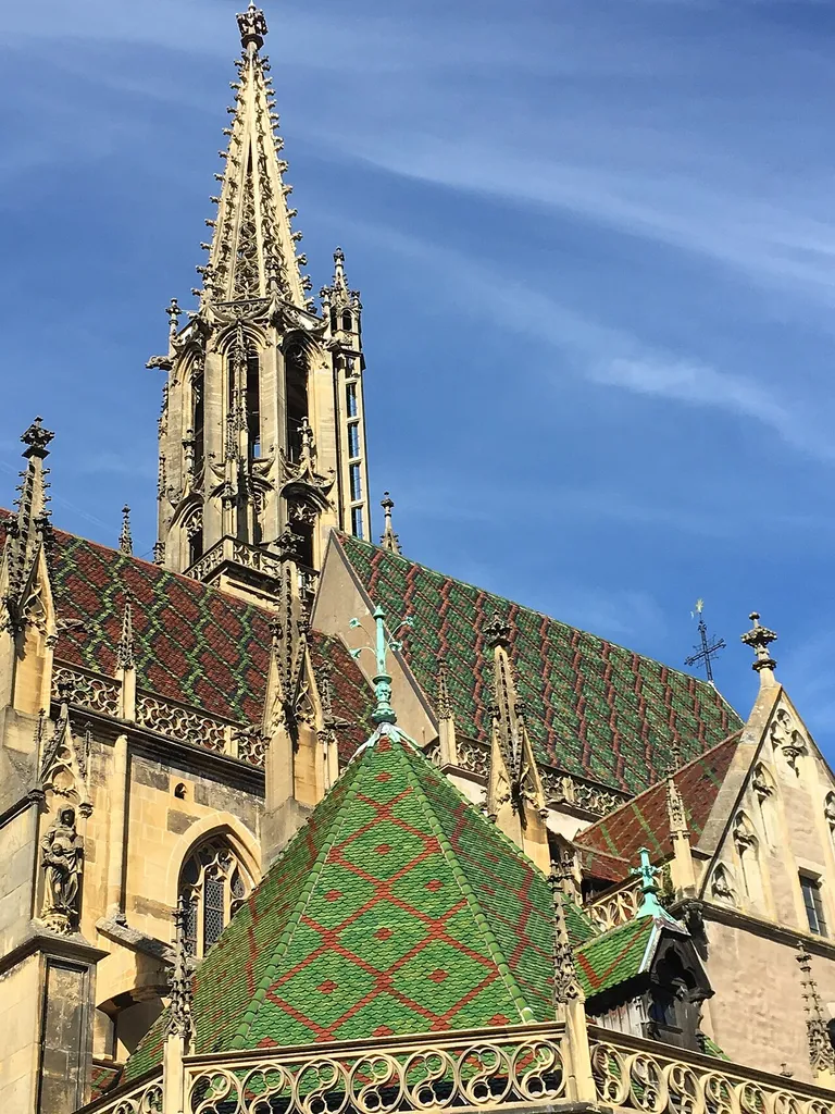 The south side of St. Theobald's church in Thann, France, highlighting the colorful roof and the spire