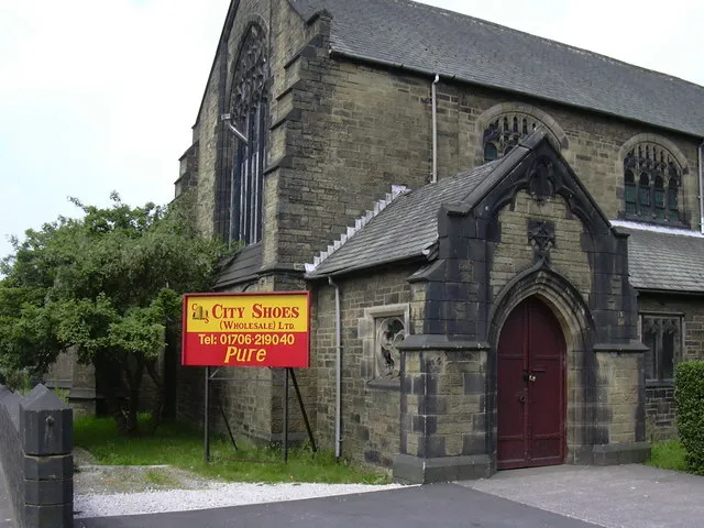 South porch of the former parish church of St John The Divine, Cloughfold, Lancashire, seen from the southeast. The church was completed in 1890, deconsecrated in 1976 and now the premises of a shoe wholesaler.