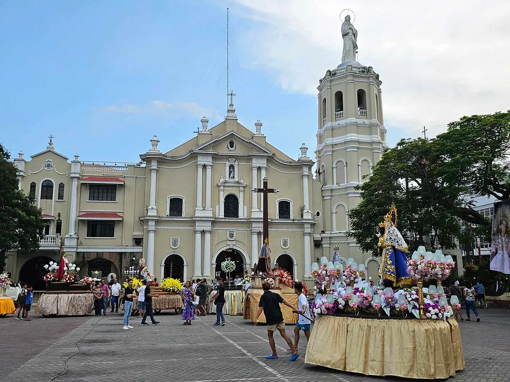 Facade of the Malolos Cathedral with several religious floats being prepared in front of the church.