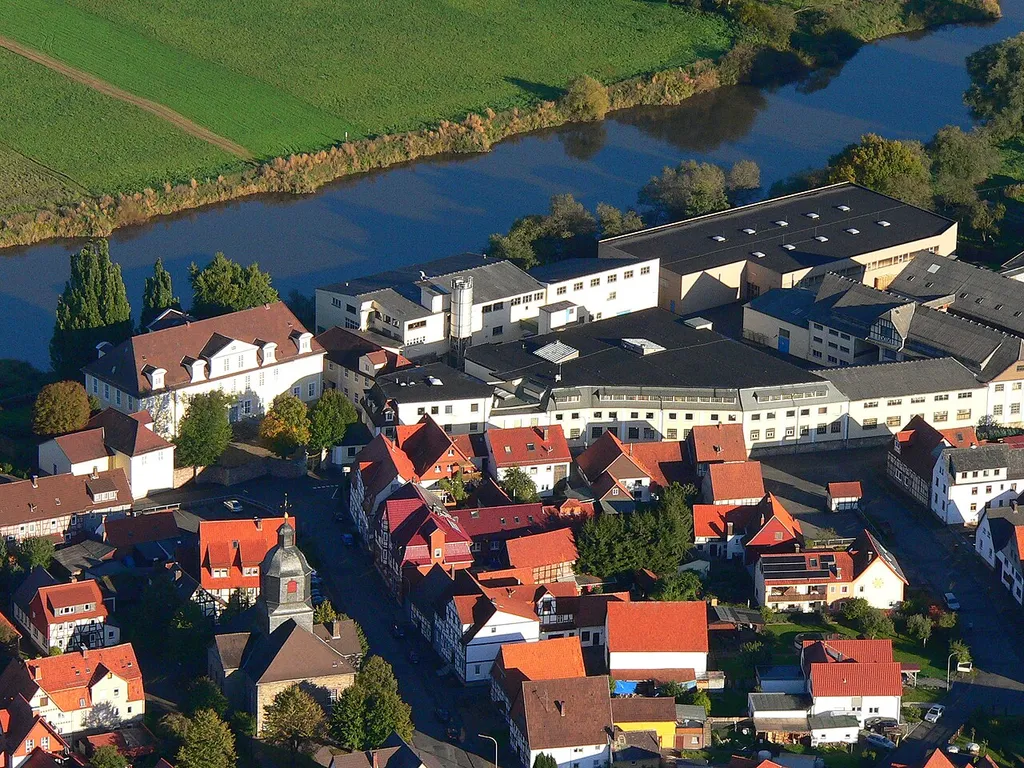 Jagdschloss Landgraf Carls in Reinhardshagen-Veckerhagen, Hessen, Deutschland (links oben am Weserufer). Rechts daneben die Farbenfabrik G. E. Habich´s Söhne auf dem Areal der ehemaligen Burg. Links im Vordergrund die evangelische Kirche. Aufnahme aus einem Heißluftballon.