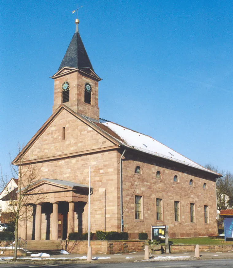 Evang. Kirche im Weinbrenner-Stil, erbaut 1830. Sie gehört zu den schönsten Kirchen des Klassizismus in Baden. Reizvoll die Ausführung in rotem Sandstein, sowie eine kleine Säulenhalle. Statt eines Kirchturmes belebt ein Dachreiter die Vorderseite des Langhauses. Auf der Eingangsseite lassen sich ungewöhnlicherweise gleich drei Dreiecksgiebel sichten : die Säulenhalle, das Langhaus und der Dachreiter zeigen dieses typisch klassizistische Würdesymbol in verschiedenen Größen.