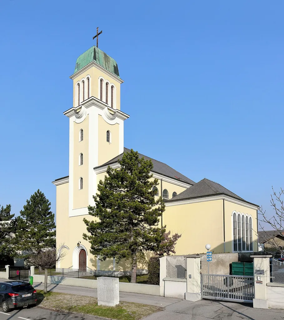 Südwestansicht der röm.-kath. Pfarrkirche zur Kreuzerhöhung in der burgenländischen Marktgemeinde Kittsee.Die dreischiffige Kirche hat einen rd. 36 m hohen (inklusive Kreuz) eingebundenem Westturm mit haubenförmigem Helm und eine halbrunde Apsis. Die Kirche mit einem Fassungsraum für rund 1250 Personen wurde nach den Plänen der Architektin Helene Koller-Buchwieser vom Baumeister Stefan Wilhelm Haderer ab 1948 errichtet und am 16. Nov. 1952 von Bischof Josef Schoiswohl eingeweiht.