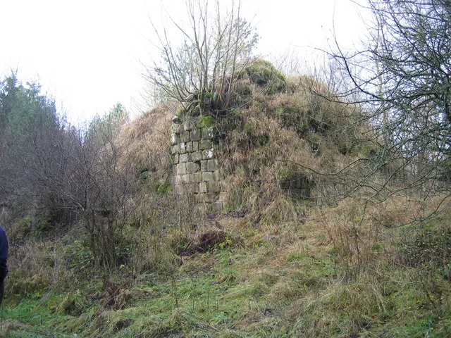 Simonburn Castle. Keys to the Past Web Site: Simonburn Castle stands on a steep hill formed by the junction of two streams. The remains of a 13th century tower house lie at its core. Although it was repaired in the 18th century, and used for a time as an eyecatcher for Nunwick Park, the upper storeys have now collapsed. The tower was built of small stone blocks. Only the ground floor basement of the tower stands today, which has become filled in with rubble.