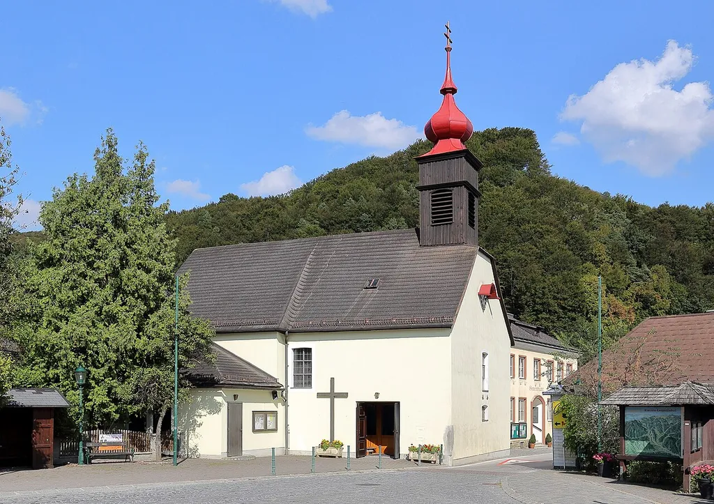 Westansicht der röm.-kath. Pfarrkirche hl. Leopold in der niederösterreichischen Gemeinde Klausen-Leopoldsdorf. Eine einfache Saalkirche mit Schopfwalmdach und Dachreiter. Sie entstand 1780 durch Umbau und wesentliche Erweiterung einer steinernen Kapelle, die in den 1750er Jahren errichtet wurde. Der Dachreiter mit Zwiebelhelm stammt aus dem Jahr 1840.