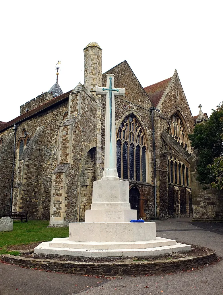 The memorial cross stands in the Churchyard bears the names and initials of 145 men from the First War and 48 from the Second plus one from the Gulf War. In the backgorund is the parish church of St Mary the Virgin. See also http://www.roll-of-honour.com/Sussex/Rye.html