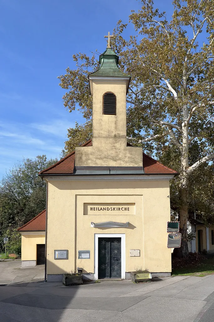 Ostansicht der Heilandskirche in der niederösterreichischen Marktgemeinde Spillern.Die Kirche wurde zum Großteil von Johann Michael Harmer gestiftet und am 15. Aug. 1831 als röm.-kath. Kapelle „Mariahilf“ geweiht. Nach dem Neubau der heutigen kath. Pfarrkirche Spillern (geweiht am 5. Sept. 1965ː [1]) wurde die Kapelle 1967 an die evangelische Pfarrgemeinde Stockerau verkauft und am 28. Sep. 1969 als „Heilandskirche“ neu geweihtː [2]. Nachdem die Kirche seit 2012 von der evangelischen Pfarrgemeinde nicht mehr genutzt wurde, wird sie seit dem 1. Nov. 2024 in Kooperation mit der rumänisch-orthodoxe Pfarre Krems von dieser für regelmäßige Gottesdienste genutztː [3].