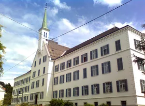 Kirche und Konvent der Schwestern vom Hl. Kreuz mit Zaun und Lourdes Grotte