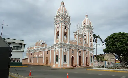 Cathedral of Our Lady of the Rosary of Cabimas. See of the Roman Catholic Diocese of Cabimas. Its located on the corner of Independencia street with Miranda street in Cabimas, Zulia, Venezuela. The church was built in 1829 by initiative of Mrs Juana Villazmil and remodeled to its current form in 1965. At the right corner a Cabimas tree is visible, the city is named after the tree. To the right of the church you can see the parsonage, and to the left of the church you can see the see of the Carmen Herrera civil parish and Cabimas postal service headquarters with a cross on the roof.