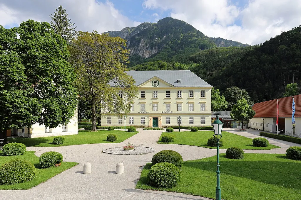 Südansicht des Schlosses Reichenau in der niederösterreichischen Marktgemeinde Reichenau an der Rax.Eine dreiflügelige Anlage mit mächtigem Eckturm im Nordwesten. 1829/30 wurde nach Plänen von Jacob Aigner das Schloss prägend umgebaut und Zubauten errichtet. Unter anderem wurde der dominierende Eingangstrakt im Süden unter Belassung der Fundamente neu errichtet. Im Hintergrund der Feichtaberg (1381m).