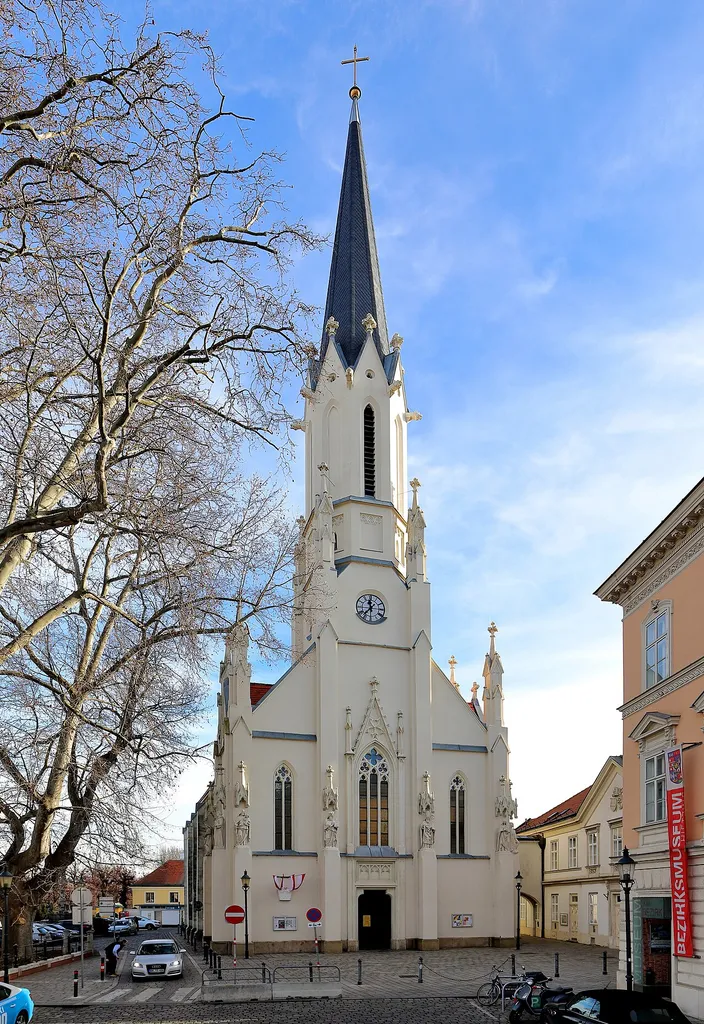 Westansicht der röm.-kath. Pfarr- und Wallfahrtskirche Maria Hietzing im 13. Wiener Bezirk Hietzing.Nach Zerstörung der Vorgängerkirche 1683 durch die Türken wurde sie 1685 neu aufgebaut. Mitte des 19. Jahrhunderts (um 1865) wurde das Gotteshaus umgebaut und nach den Plänen von Carl Roesner Richtung Westen erweitert. Dabei wurden die Westfassade und der Glockenturm im neugotischen Stil errichtet.